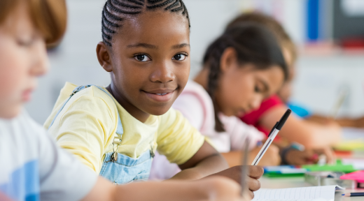 Students in a classroom writing in notebooks.