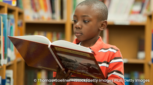 A student reading a book in a library.