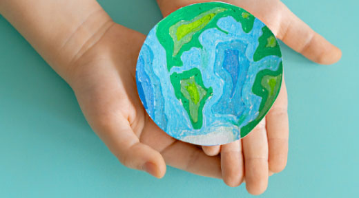 A hand drawn earth cutout cupped in a students hands.