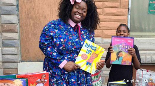 Photo of Storybook Maze holding a book and accompanied by a young person also holding a book.